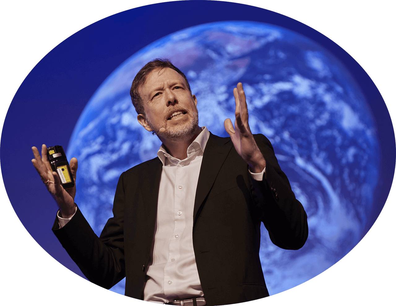 Porträt von Dr. Nicolas Dierks beim Keynote-Vortrag, mit weiter Geste erklärend. Im Hintergrund ist ein Bild des Planeten Erde zu sehen.