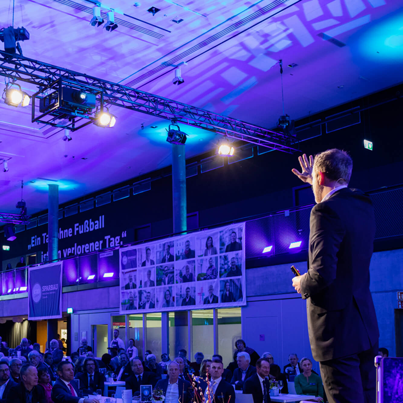 Keynote-Speaker Dr. Nicolas Dierks bei einem Vortrag von hinten zu sehen, wie er das Publikum zum Mitmachen animiert.