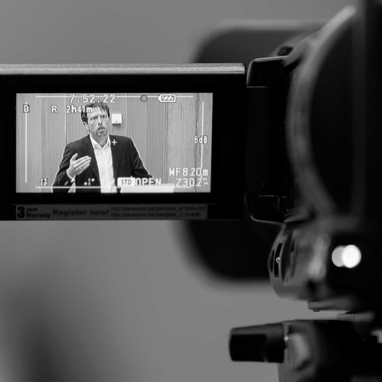 Philosoph Dr. Nicolas Dierks beim Keynote-Vortrag, zu sehen auf dem Monitor einer Filmkamera.